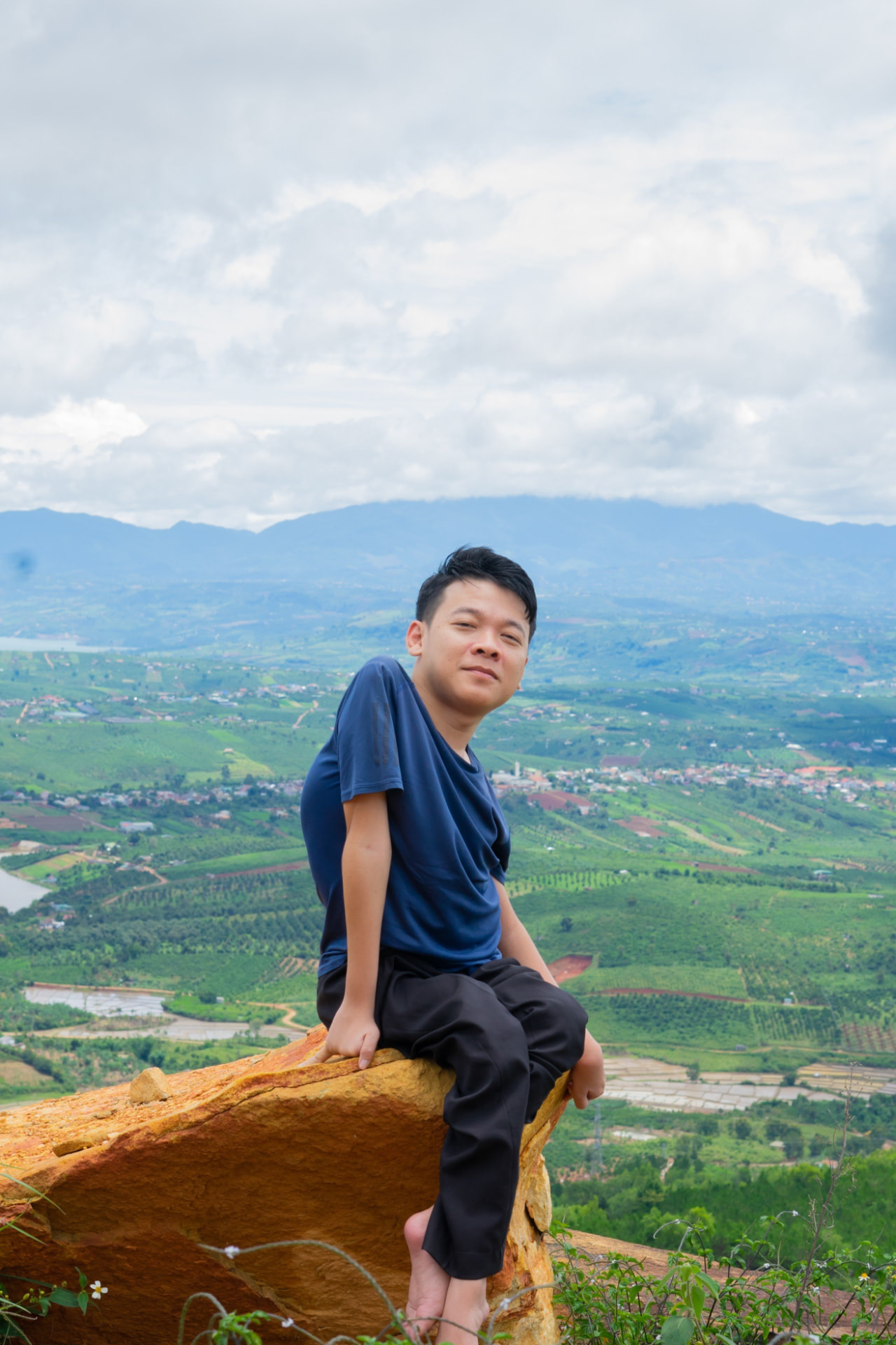 Nguyễn Trung Hậu sitting above a green valley beneath an open sky